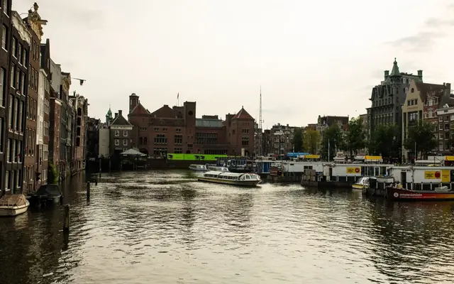 A picturesque view of Amsterdam canals with historic buildings and boats on a cloudy day.