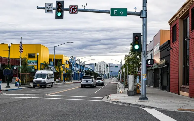 Vibrant morning on a bustling street in downtown Anchorage, Alaska, with colorful buildings and traffic.