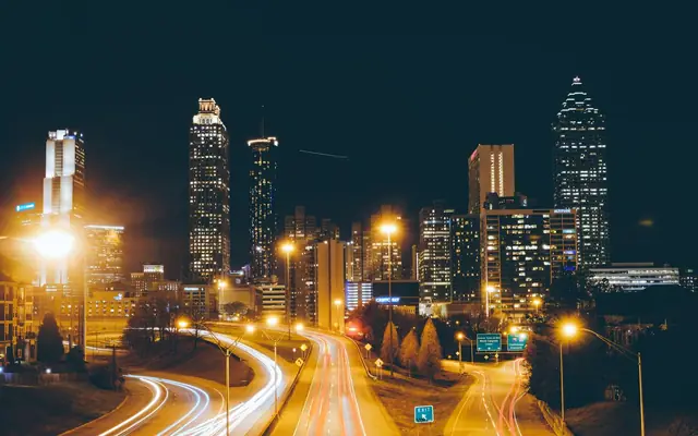 Stunning long exposure photo of Atlanta skyline at night with traffic light trails creating dynamic movement.