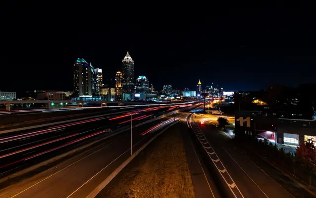 Vibrant night shot of Atlanta skyline with captivating light trails on a busy highway.