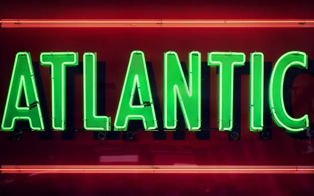 Green and red neon sign displaying the word 'Atlantic' on a dark background.