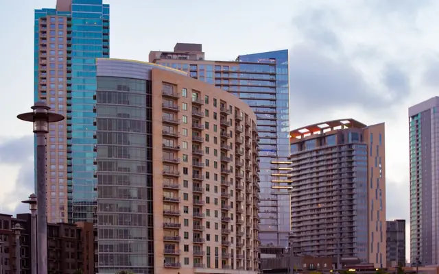 View of contemporary skyscrapers in downtown Austin, Texas with a cloudy sky backdrop.