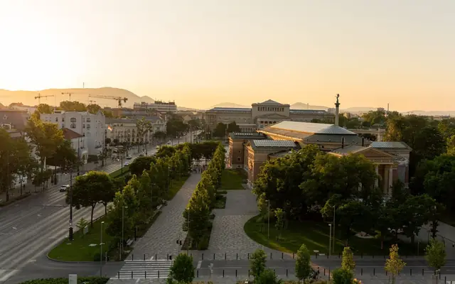 Stunning aerial view of Budapest cityscape at sunset, showcasing iconic architecture and urban greenery.
