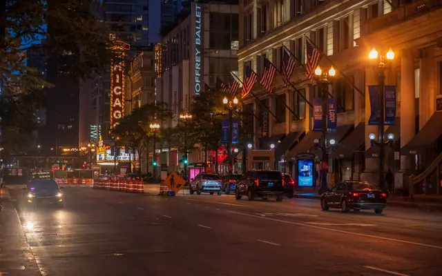 View of a bustling Chicago street at night featuring the iconic Chicago Theater sign and urban nightlife.