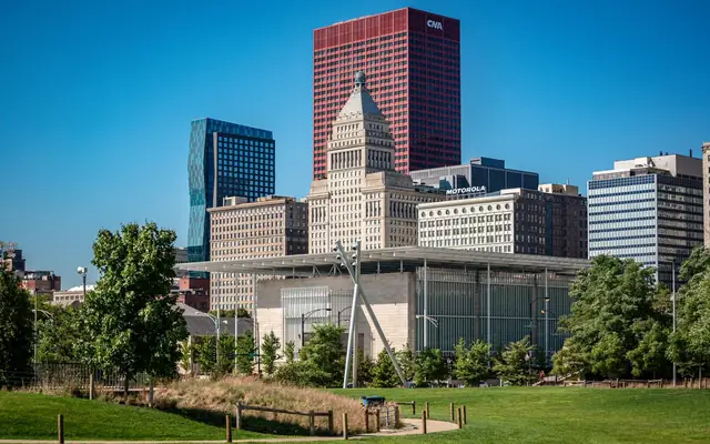 Panoramic view of Chicago's iconic skyline with lush park in the foreground and clear blue skies above.