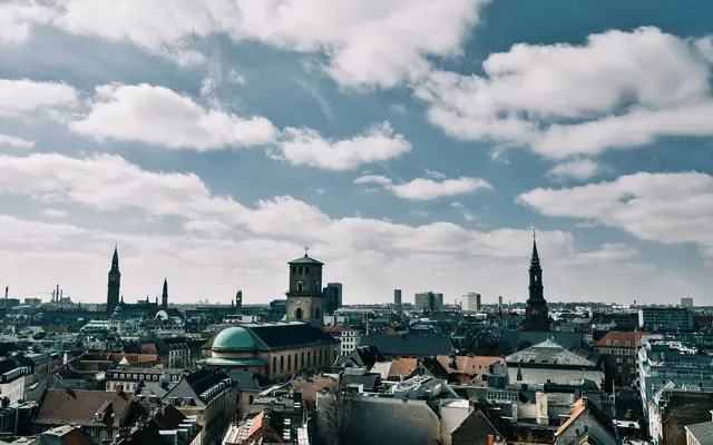 Stunning aerial view of Copenhagen's cityscape under a vibrant blue sky, showcasing historic spires and architecture.