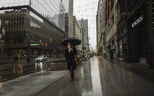 Person walking with an umbrella on a rainy day in downtown Detroit, showcasing urban life.
