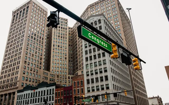 Low-angle view of Detroit skyscrapers and Congress street sign, capturing the urban essence of downtown.