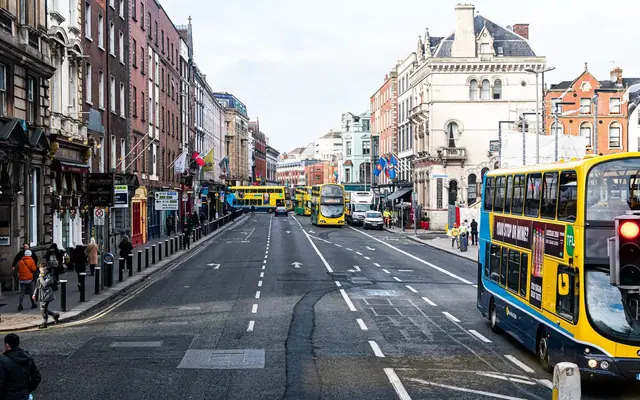 Vibrant city street scene in Dublin with buses and pedestrians on a busy day.