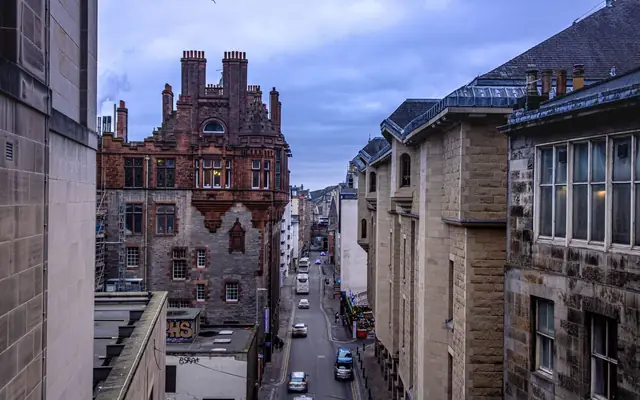 View of a narrow street in Edinburgh with historical buildings on an overcast day.