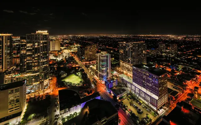 Breathtaking drone view of modern Fort Lauderdale city district with illuminated street and skyscrapers against dark night sky