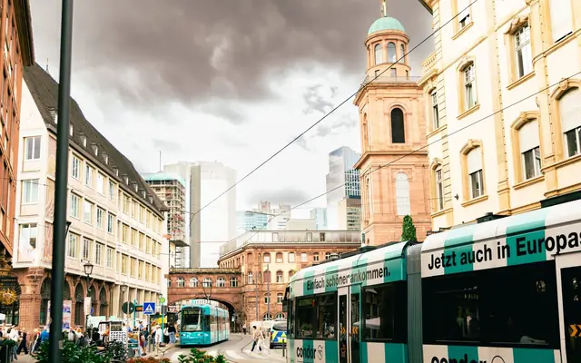 Urban scene in Frankfurt, Germany, showcasing trams and historic architecture under cloudy skies.