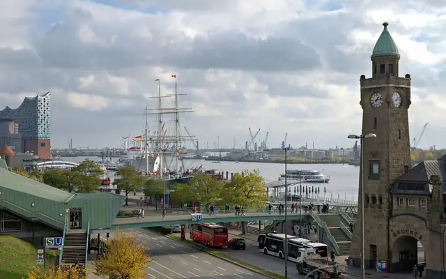 A busy day at Hamburg's harbor featuring the Elbphilharmonie, historic ships, and clock tower.