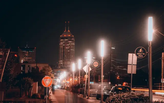 Vibrant night scene of Indianapolis with illuminated pathway and city skyline in view, showcasing urban life.