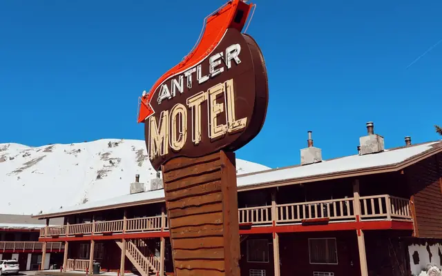 Iconic Antler Motel sign against snowy mountain backdrop in Jackson, Wyoming.