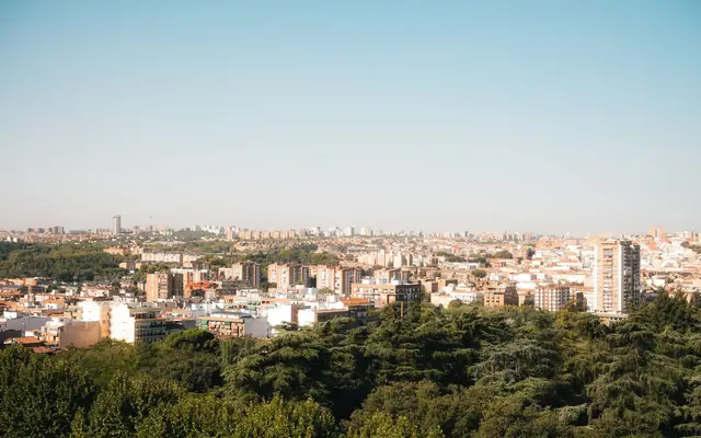 Elevated panoramic view of Madrid's urban landscape with lush greenery and clear skies.