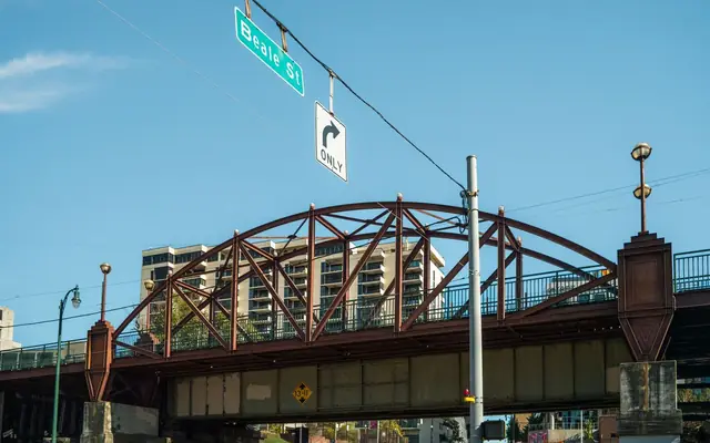 View of the iconic Beale Street bridge in Memphis with cityscape backdrop under clear blue skies.