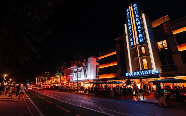 Vibrant nightlife scene in Miami's iconic Art Deco district with neon lights and crowds.