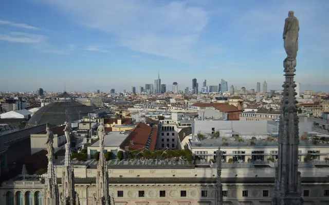 Captivating aerial view of Milan's skyline from atop the Duomo with a clear blue sky backdrop.