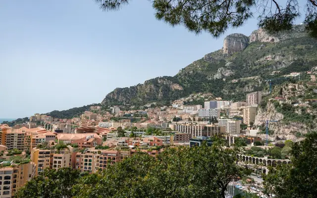 A breathtaking view of Monaco's cityscape with lush mountains and Mediterranean coastline.
