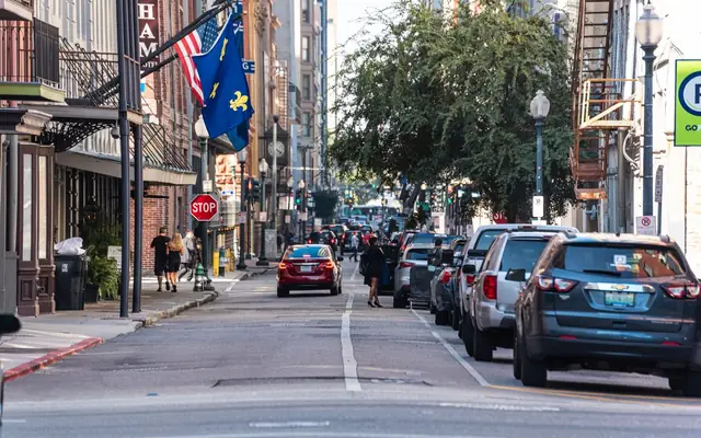 Bustling street in New Orleans with cars, pedestrians, and vibrant architecture.