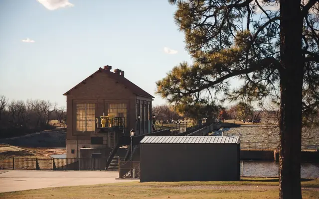 Charming view of a historic building near Lake Overholser Dam, Oklahoma City, with clear skies and lush greenery.