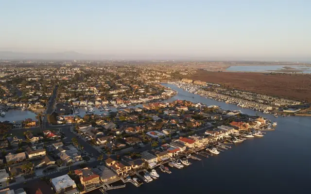 Stunning aerial view of Huntington Beach harbor showcasing boats and residential area at sunset.