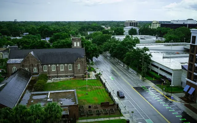 Aerial view of Orlando's wet streets and greenery after rain, featuring historic building.