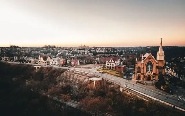 Stunning aerial view of Pittsburgh at sunset, showcasing a historic church and charming neighborhood.