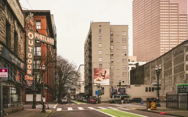 Urban street scene in downtown Portland featuring historic neon sign and modern architecture.