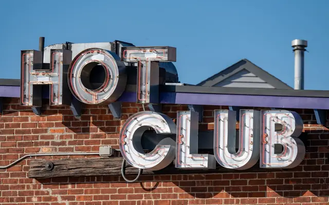 Iconic neon Hot Club sign against a brick wall in Providence, Rhode Island, original landmarks.
