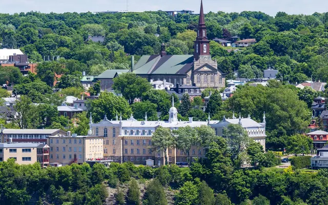 Stunning aerial view of Quebec City's historic buildings surrounded by lush greenery in summer.