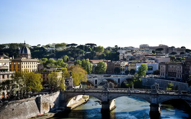 Beautiful view of Ponte Sant'Angelo spanning the Tiber River in Rome, Italy under a clear sky.