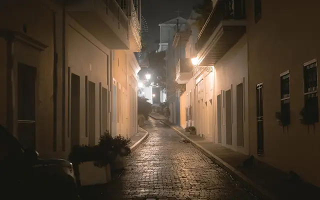 Explore the atmospheric charm of a narrow street in Old San Juan at night, showcasing historic colonial architecture.