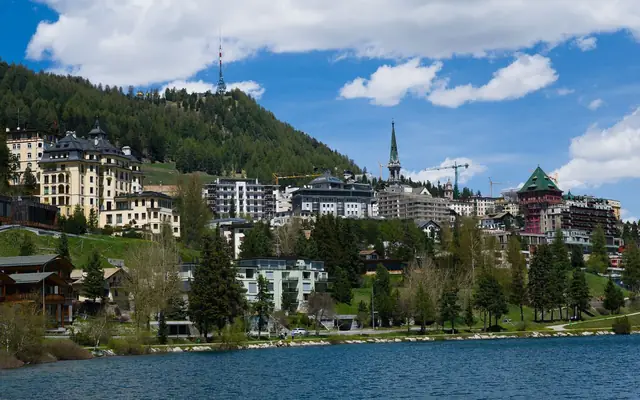 Beautiful day view of St. Moritz with its classic architecture, surrounded by mountains and a serene lake.