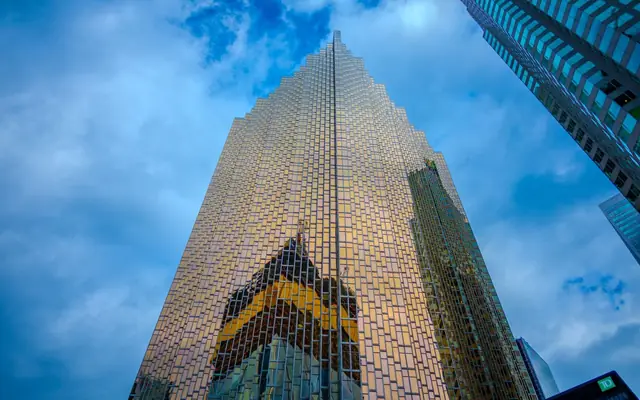 Imposing skyscraper with a reflective glass facade against a blue sky.