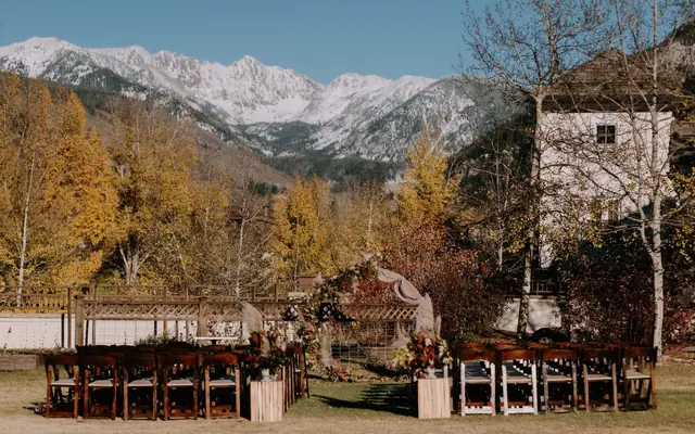 Outdoor wedding venue in Vail, Colorado, with a backdrop of autumn foliage and snowcapped mountains.