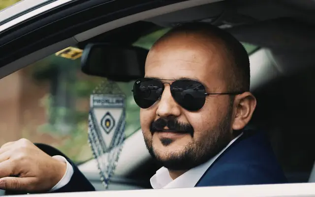 Chauffeur in a suit and sunglasses at the wheel of a car